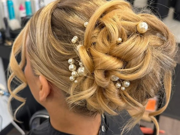A blonde updo set with pearl pins, styled at Mane Escape Studio