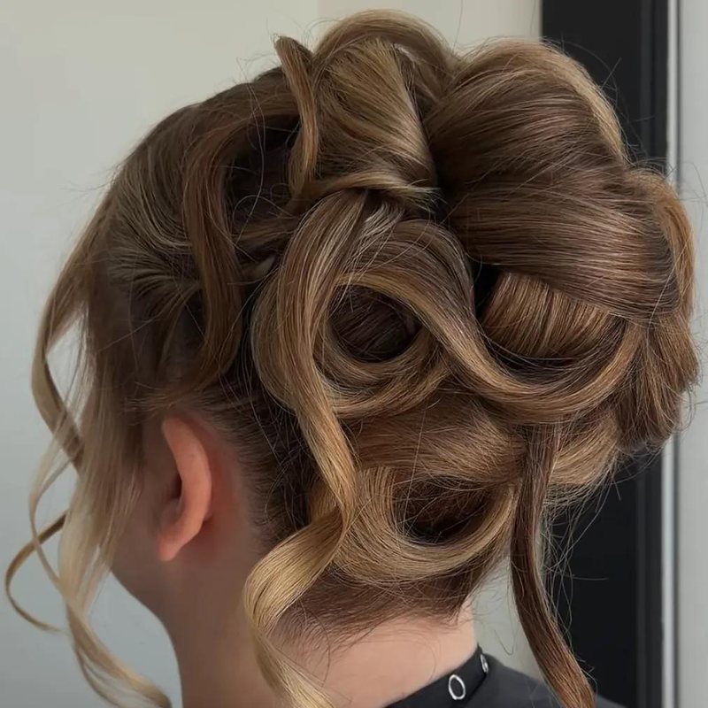 A curled bronde updo with loose face-framing pieces, styled at Mane Escape Studio