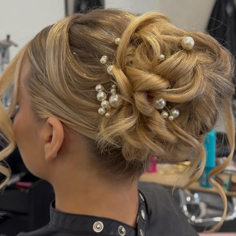 A blonde updo set with pearl pins, styled at Mane Escape Studio in Benwood