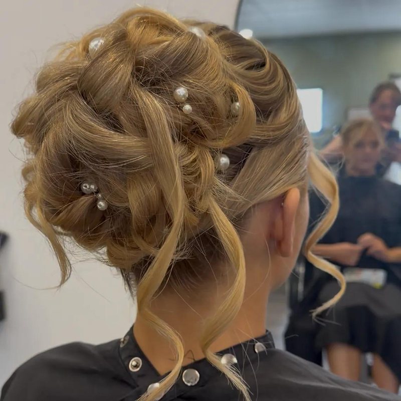 A textured blonde updo dressed with pearl pins, seen from behind