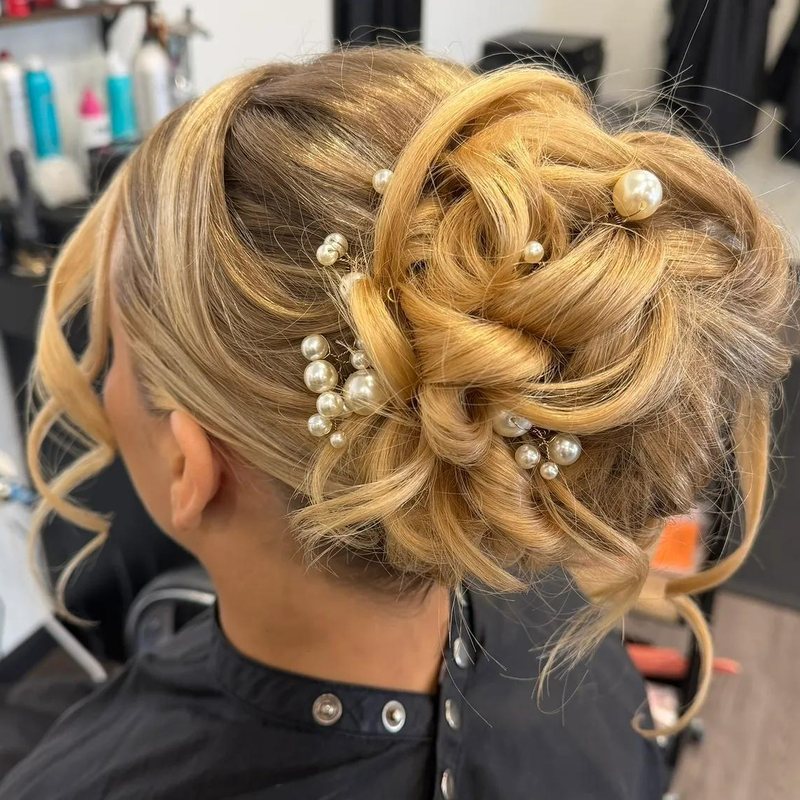 A pearl-pinned blonde updo styled for a special event at Mane Escape Studio